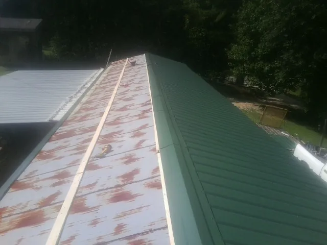 Old rusted panels beside newly installed green metal roofing — Wind Damage Roof Repair by Roofing Brothers in Centennial