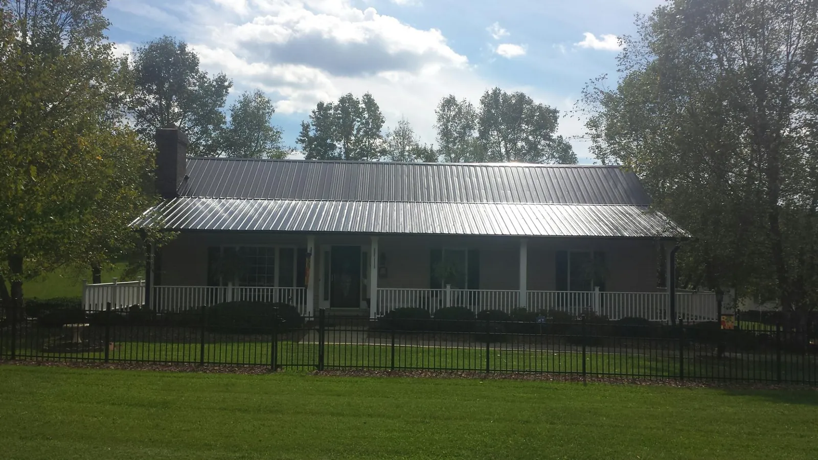 Gray metal roof on a brick ranch with a full width front porch — Gutter Guard Installation work by our crew in Centennial