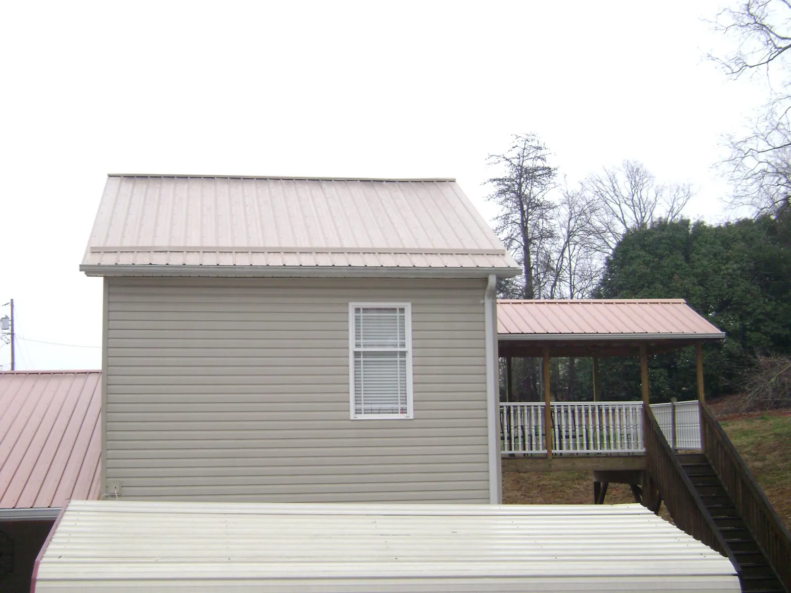 Tan metal roofs on a two story addition and attached porch, from a Roof Replacement job in Centennial