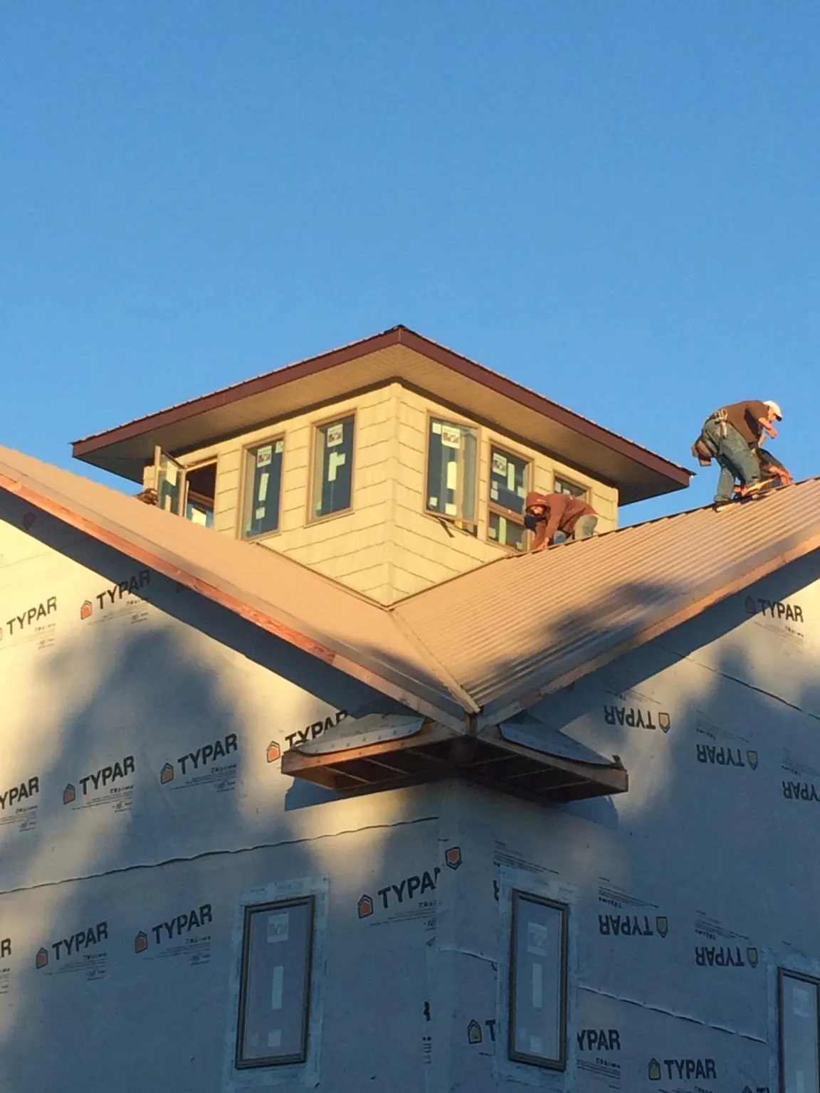 Roofers working around a rooftop cupola on a new metal roof at sunset — Roof Waterproofing in Centennial by Roofing Brothers